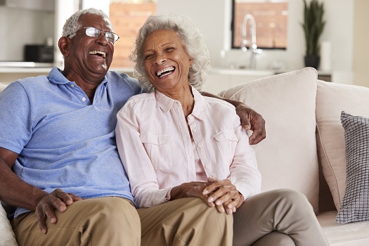 Loving Senior Couple Sitting On Sofa At Home And Laughing Together